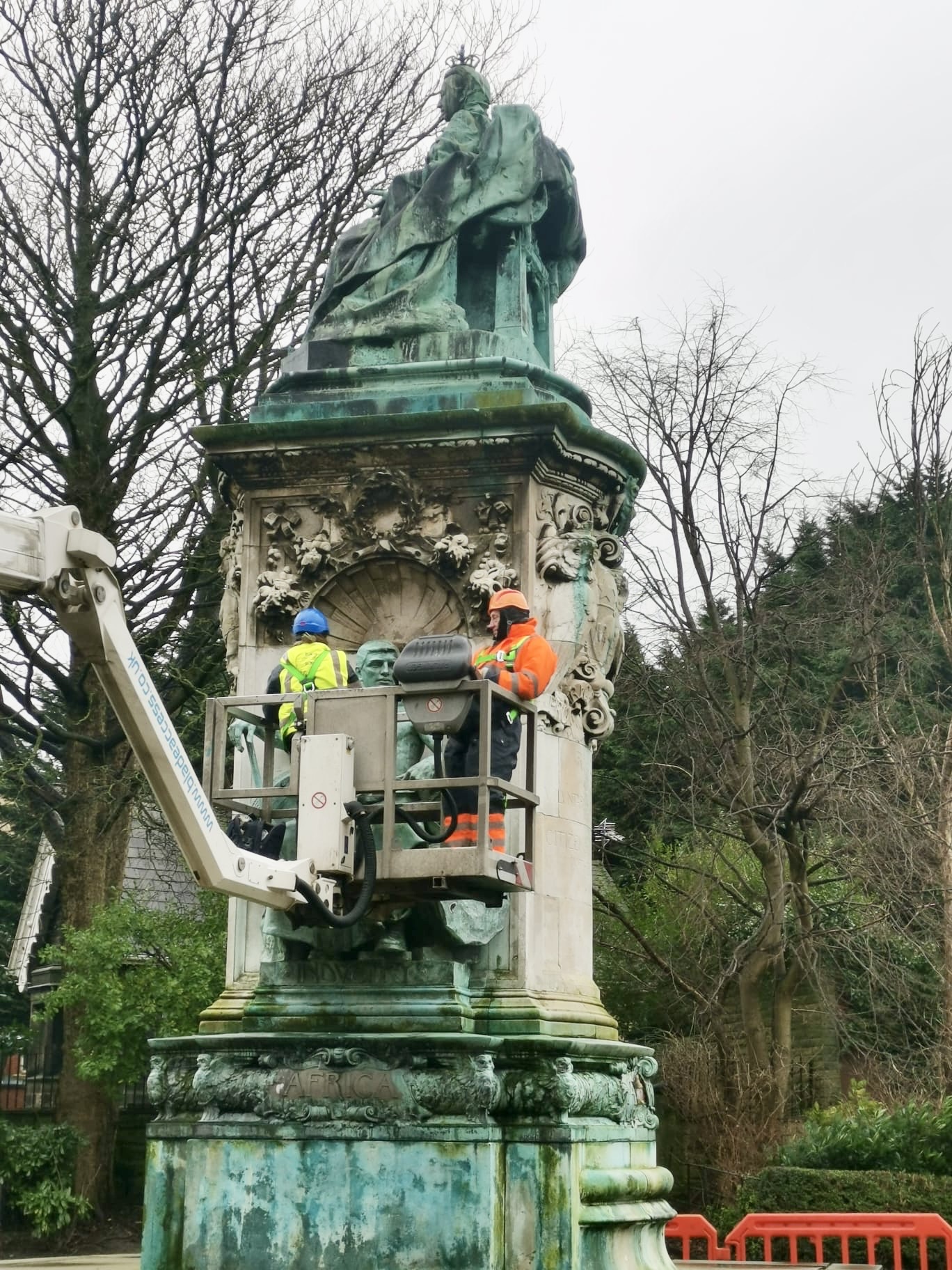 Specialist bronze maintenance team working at height using a cherry picker